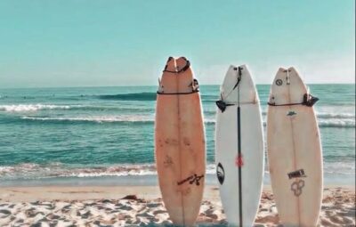 Surfboards on a sandy beach with ocean waves in the background