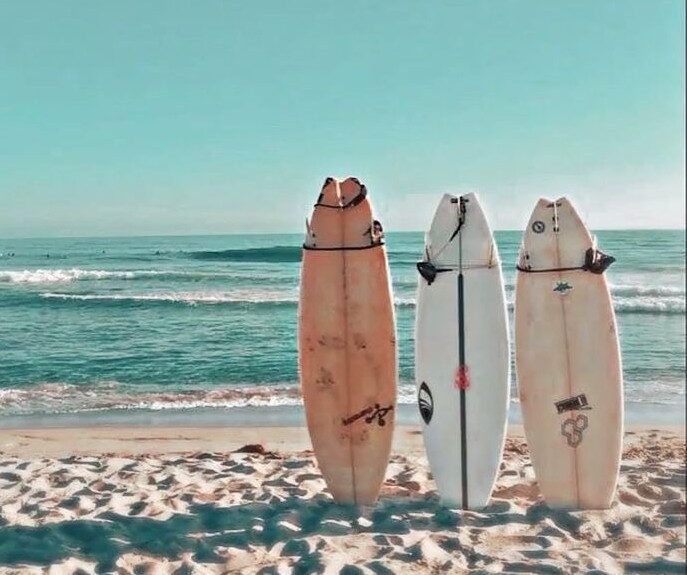 Surfboards on a sandy beach with ocean waves in the background