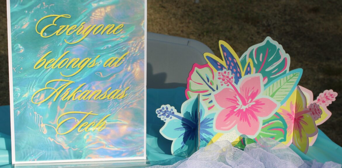 Sign that says "Everyone belongs at Arkansas Tech" on table with pride themed buttons