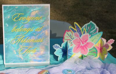 Sign that says "Everyone belongs at Arkansas Tech" on table with pride themed buttons