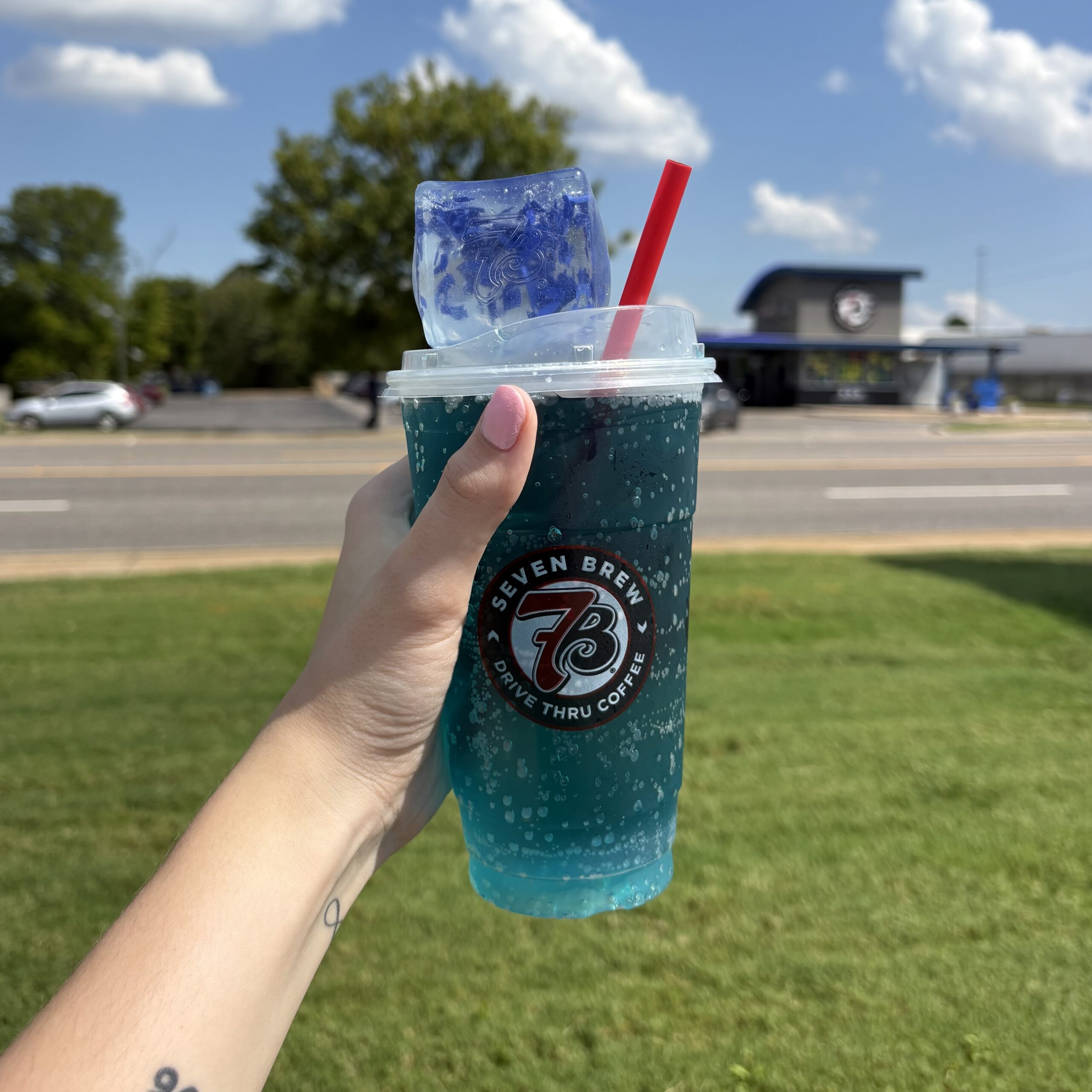 Blue 7 Brew Doh squishy and 7 Energy drink in front of 7 Brew building